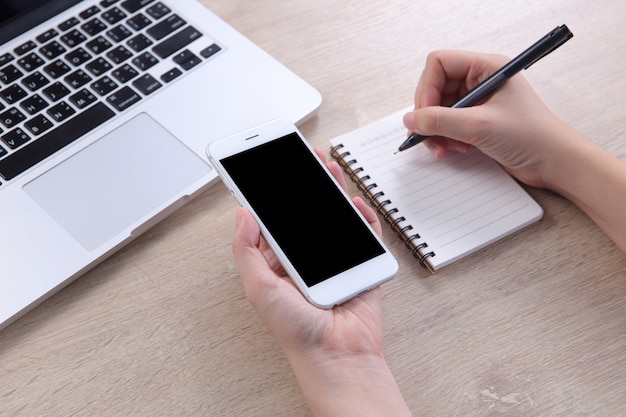 Femme d'affaires détenant maquette smartphone avec l'écriture sur le carnet de notes