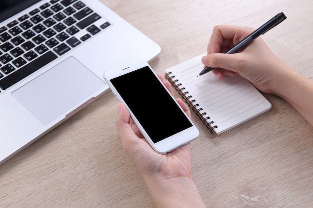 Femme d&#39;affaires détenant maquette smartphone avec l&#39;écriture sur le carnet de notes