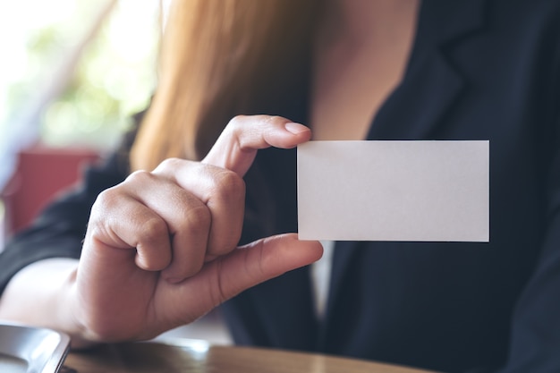 Photo une femme d'affaires détenant et montrant une carte de visite vide