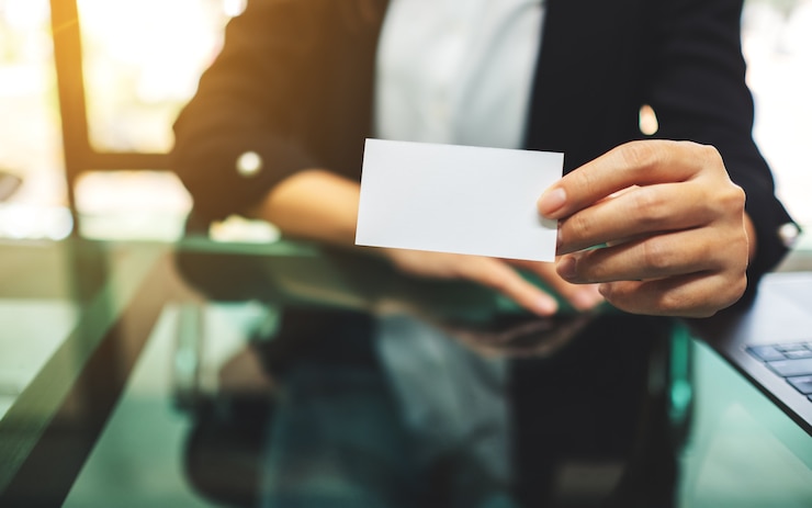 Photo une femme d'affaires détenant et montrant une carte de visite vierge au bureau