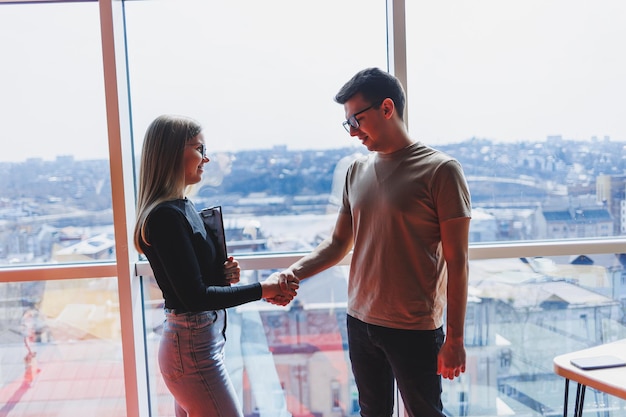 Une femme d'affaires avec des documents dans des verres se tient avec un gestionnaire d'homme tenant une réunion d'affaires d'entreprise dans un bureau moderne Concept de réunion d'affaires Mise au point sélective de l'espace libre