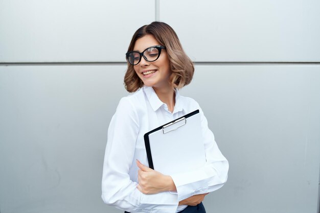 Femme d'affaires avec des documents en mains dans la rue près du bâtiment