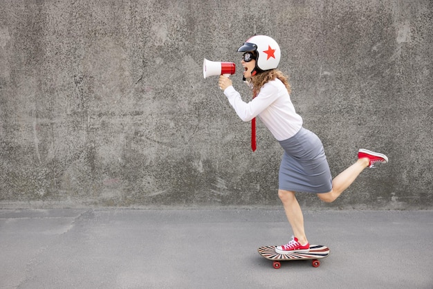 Femme d'affaires drôle faisant du skateboard en plein air