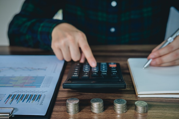 Femme d&#39;affaires, économiser de l&#39;argent et analyser les comptes financiers sur le bureau.