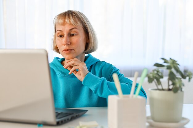 Femme d'affaires écoutant une conférence éducative sur ordinateur, regardant un webinaire, étudiant des cours en ligne, écrivant des notes dans un cahier papier, concept d'apprentissage en ligne