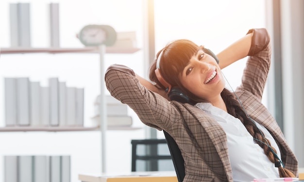 Femme d'affaires écoutant de la musique au bureau avec un casque