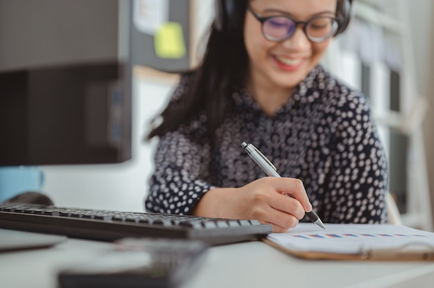 Une femme d'affaires écoute de la musique avant de travailler le matin et vérifie les graphiques sur le lieu de travail