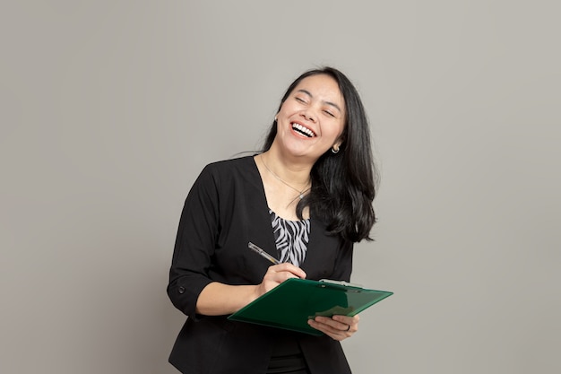 Femme d'affaires écrit sur le presse-papiers souriant joyeusement et fermant les yeux