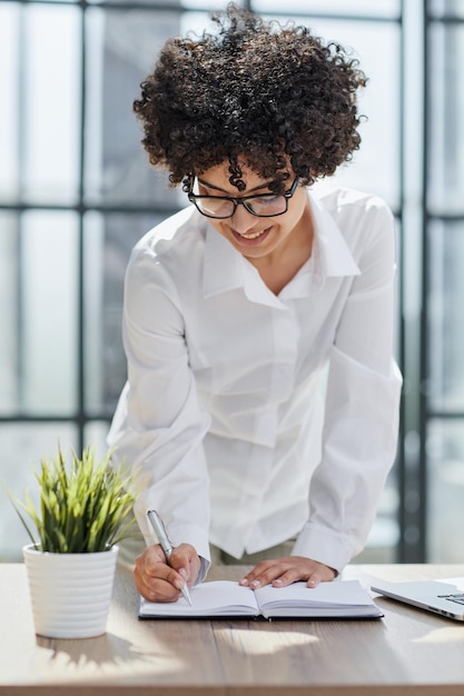 Femme d'affaires écrivant à son bureau dans un bureau moderne