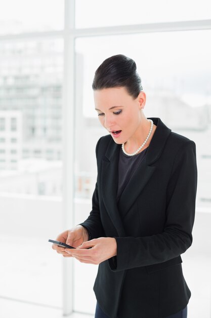 Femme d&#39;affaires élégant choqué en regardant téléphone mobile