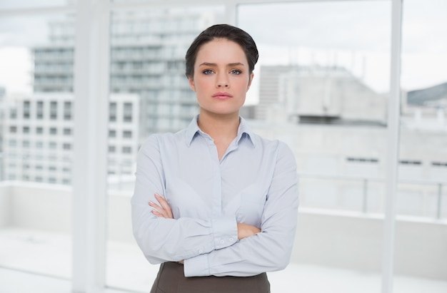 Femme d&#39;affaires élégant debout avec les bras croisés dans le bureau