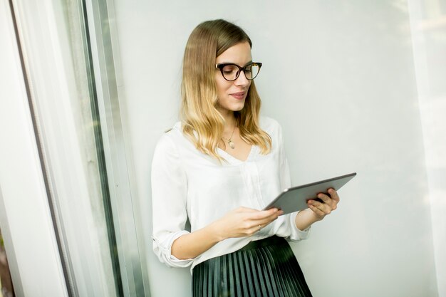 Femme d&#39;affaires élégant debout dans le bureau avec tablette numérique