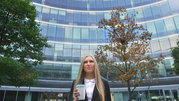 Femme d'affaires élégant avec du café dans la rue.