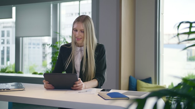 Femme d'affaires élégant avec tablette au bureau