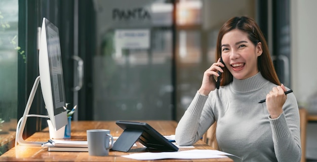 Femme d'affaires élégante assise au bureau à l'aide d'un téléphone portable et d'une tablette numérique