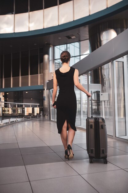 Femme d'affaires élégante avec des bagages à l'aéroport