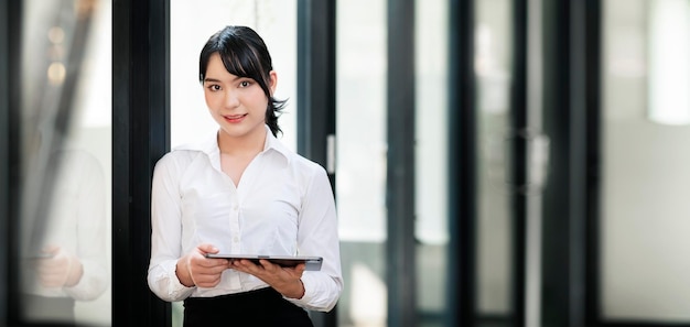 Femme d'affaires élégante debout au bureau avec tablette numérique