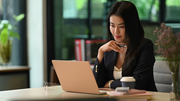 Femme d'affaires élégante du millénaire regardant un webinaire en ligne lisant des e-mails sur son ordinateur portable