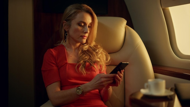 Femme d'affaires élégante envoyant des SMS sur un smartphone au soleil Dirigeant d'entreprise riche