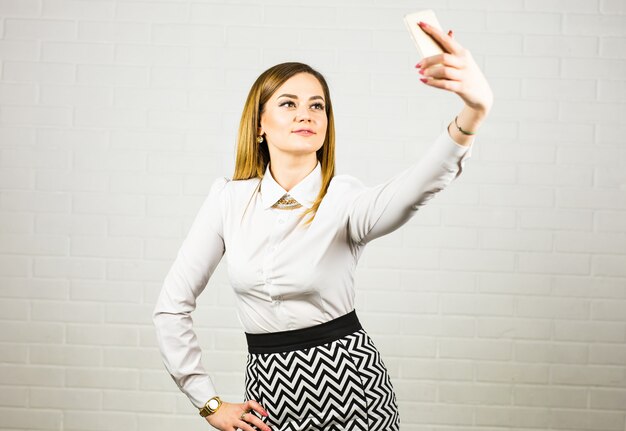 Femme d'affaires élégante faisant selfie avec téléphone portable.