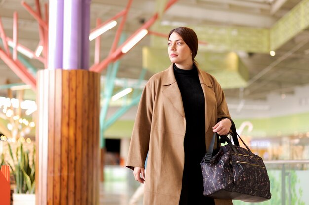 Photo femme d'affaires élégante marchant dans un centre commercial ou un aéroport portant un sac à main