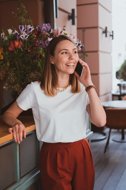 Femme d'affaires élégante parlant par smartphone au magasin de fleurs