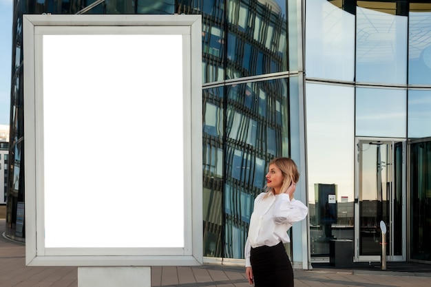 Femme d'affaires élégante en plein air contre le centre de fond. Femme en blouse dans le quartier des affaires avec espace de copie isolé blanc. Portrait de jolie femme souriante dans des vêtements de style au bâtiment