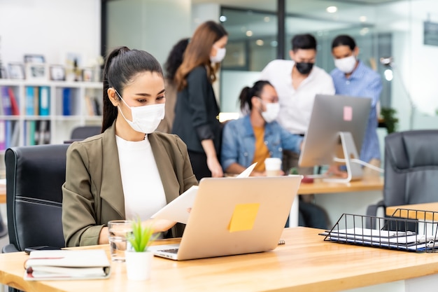 Femme d'affaires employée de bureau asiatique porte un masque protecteur pour travailler dans un nouveau bureau normal