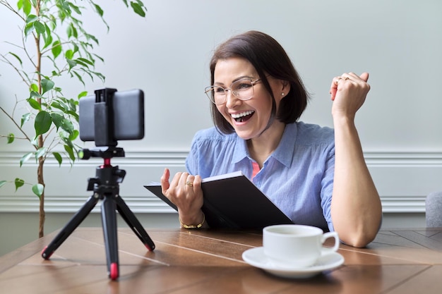 Femme d'affaires enseignante d'âge moyen travaillant en ligne à l'aide d'un smartphone