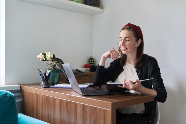 Femme d'affaires enseignante travaillant en ligne à la maison avec un ordinateur portable à l'aide d'un appel vidéo