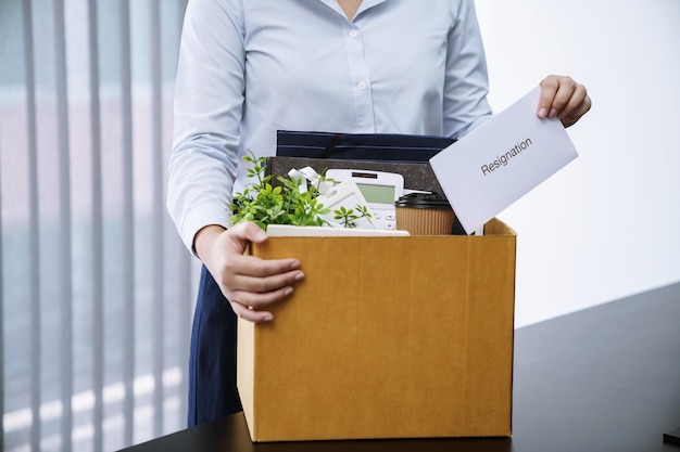 Femme d'affaires envoyant une lettre de démission et emballant des affaires démissionner déprimer ou porter une boîte en carton d'affaires par bureau au bureau Changer d'emploi ou viré de l'entreprise