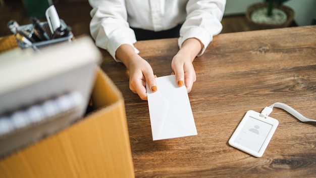 Femme d'affaires envoyant une lettre de démission et emballant des trucs Démissionner Dépresser ou transporter une boîte en carton d'affaires près du bureau au bureau Changement d'emploi ou congédié de l'entreprise