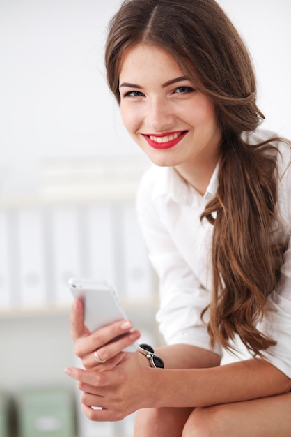 Femme d'affaires envoyant un message avec un smartphone au bureau