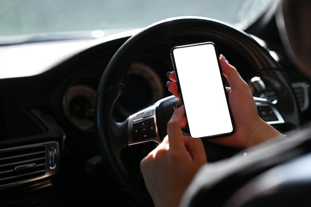 Femme d'affaires envoyant des SMS sur son téléphone portable alors qu'elle était assise dans sa voiture