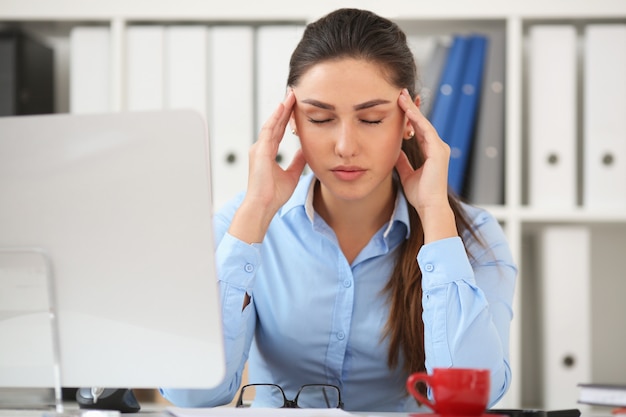 Femme d'affaires éprouvant du stress sur le lieu de travail, tenant sa main derrière sa tête