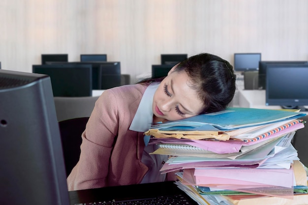 Femme d'affaires épuisée avec des documents au bureau