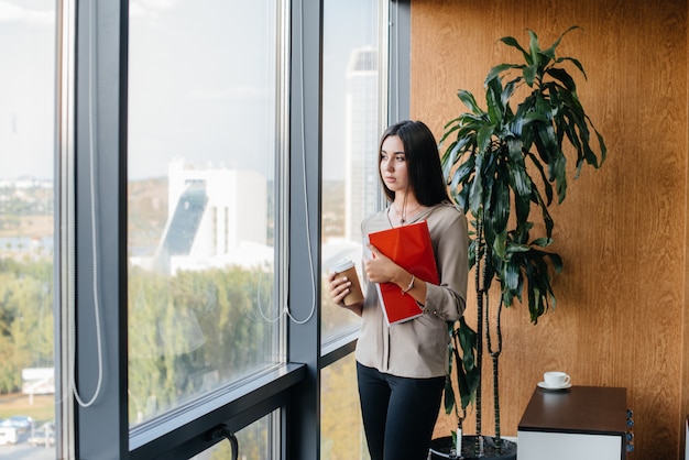 Femme d'affaires est debout dans le bureau près de la fenêtre et étudie les documents. Affaires, finance, avocat