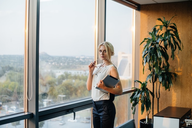 Femme d'affaires est debout dans le bureau près de la fenêtre et étudie les documents. Affaires, finance, avocat