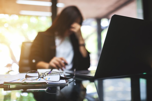 Une femme d'affaires est stressée et a mal à la tête tout en ayant un problème au travail au bureau