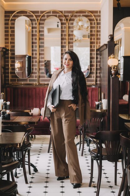 Une femme d'affaires européenne confiante dans un costume d'affaires se tient avec un ordinateur portable dans une femme d'affaires de café