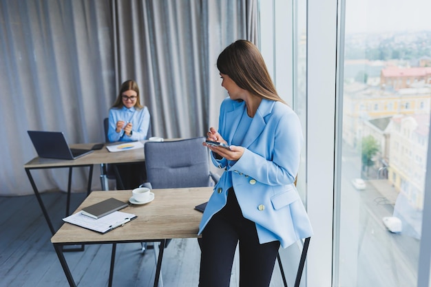 Femme d'affaires européenne tout en travaillant au bureau Jeune femme brune millénaire sérieuse dans une veste Le concept de travail indépendant et à distance Mode de vie des femmes modernes