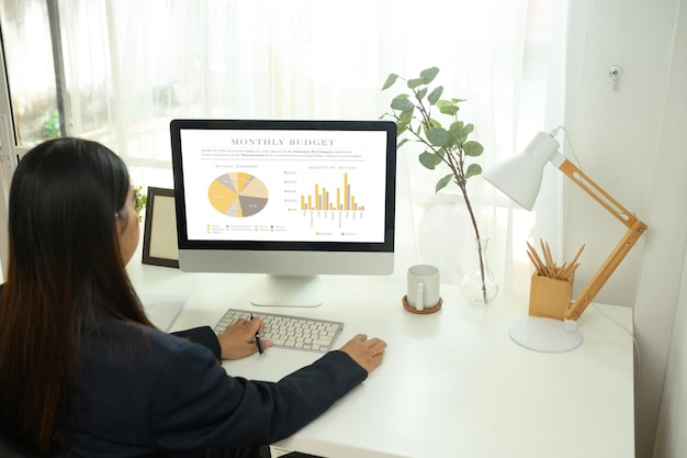 Une femme d'affaires examine un rapport financier sur un ordinateur de bureau