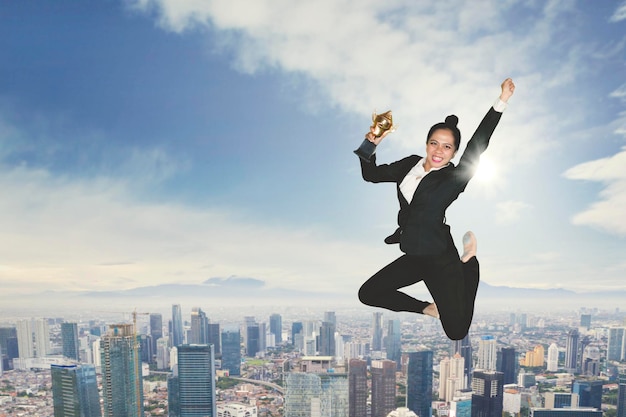 Une femme d'affaires excitée dansant avec un trophée.