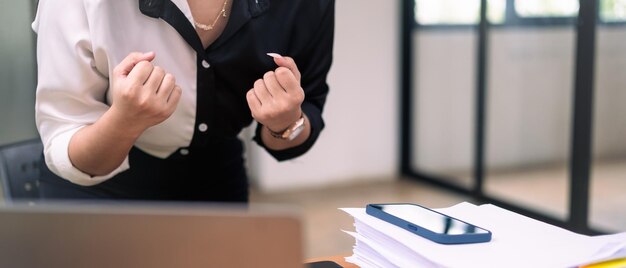 Une femme d'affaires excitée regardant l'écran de son ordinateur portable faisant le gagnant oui geste célébrant les affaires