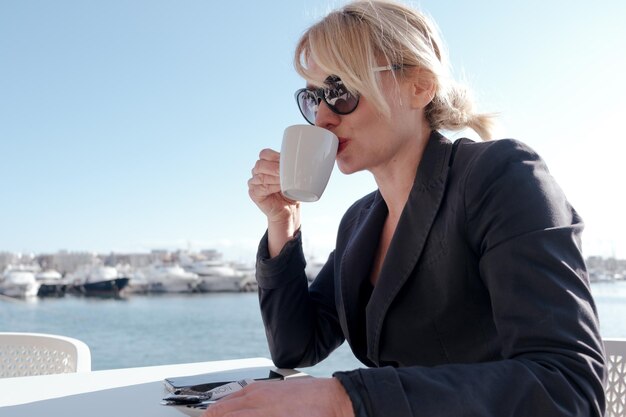 Femme d'affaires exécutive boit du café à l'extérieur