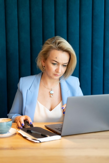 Femme d'affaires face belle caucasienne jeune ou mature femme de carrière professionnelle patron en costume d'affaires travaillant sur ordinateur portable femmes modernes entrepreneur travaillant dans un restaurant et un café petite entreprise