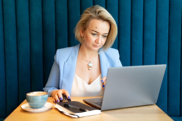 Femme d'affaires face belle caucasienne jeune ou mature femme de carrière professionnelle patron en costume d'affaires travaillant sur ordinateur portable femmes modernes entrepreneur travaillant dans un restaurant et un café petite entreprise