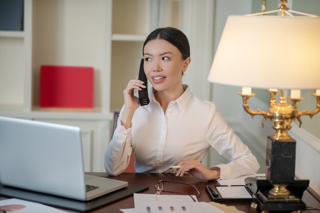 Une femme d'affaires faisant un appel téléphonique tout en travaillant