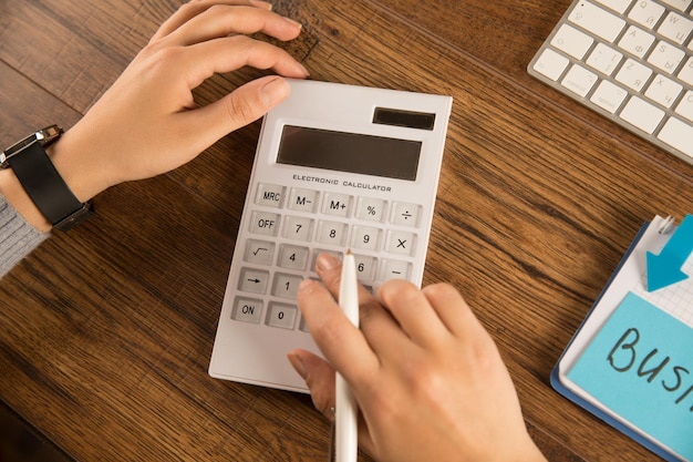 Femme d'affaires faisant des calculs dans une calculatrice