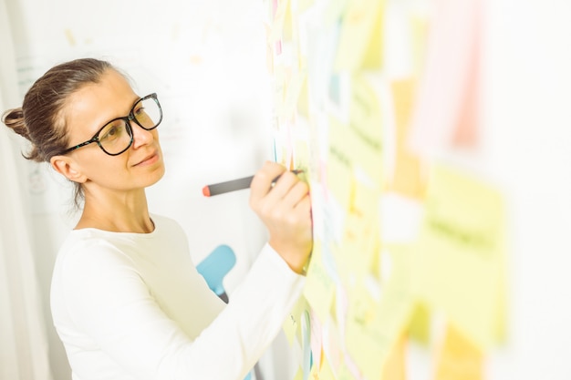 Femme d'affaires fait une note sur un autocollant en papier